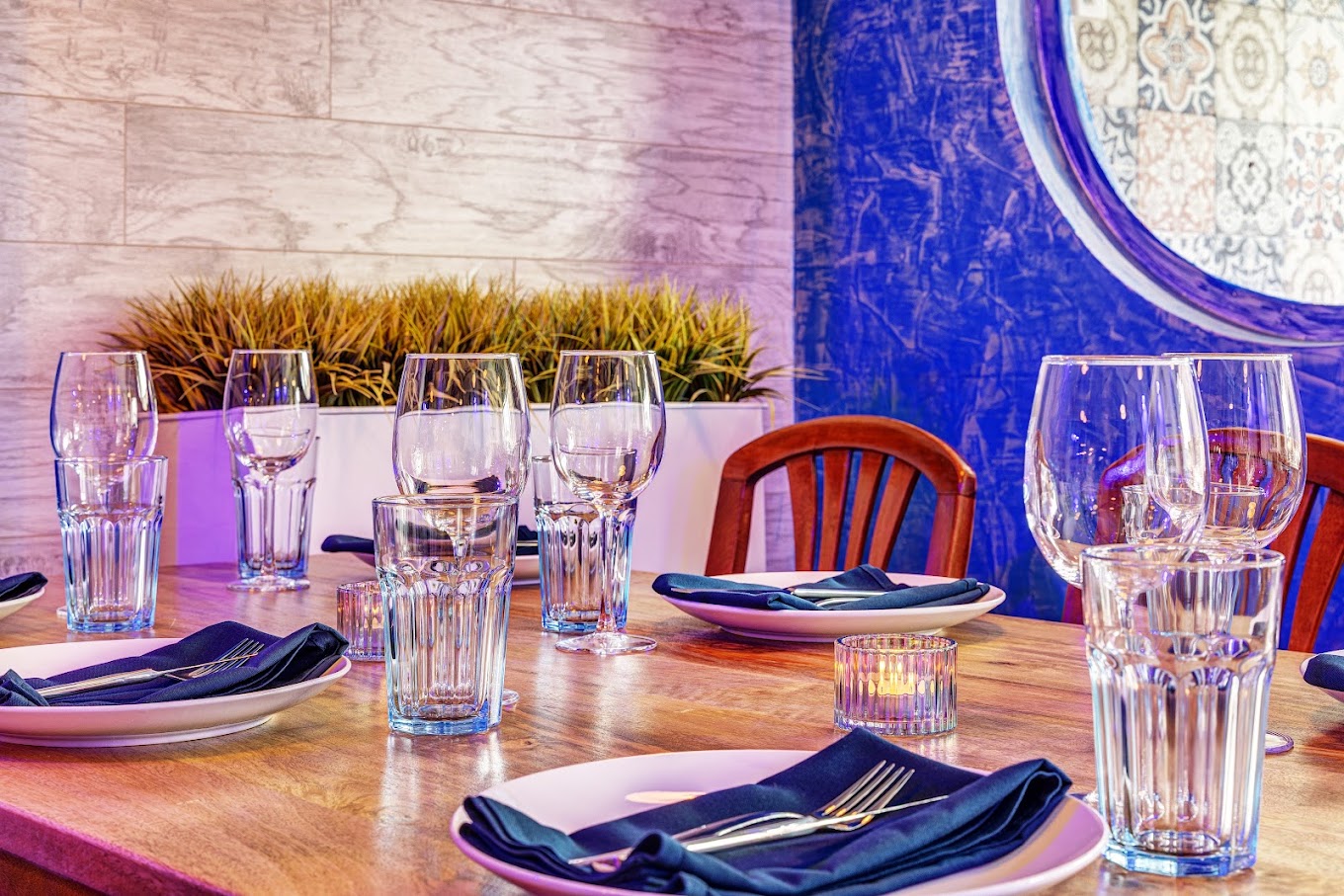 Table dressée avec verres à vin devant une banquette bleue du restaurant